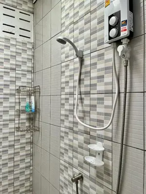a shower in a bathroom with a tiled wall at Kirin Riverside Homestay with AC, WiFi in Bangkok in Rat Burana