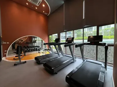 a gym with treadmills and ellipticals in a room with windows at Modern Condo Near Icon Siam & BTS Krung Thonburi in Bangkok