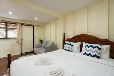 a bedroom with a large white bed and a chair at Resort Bangphlat in Bang O