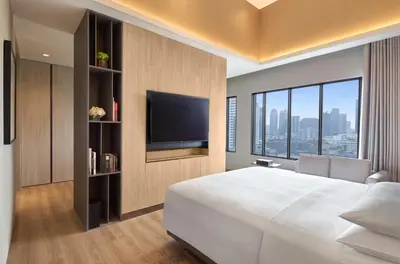 a bedroom with a large white bed and a flat screen tv at Marriott Executive Apartments, Bangkok Townhall Sukhumvit in Bangkok