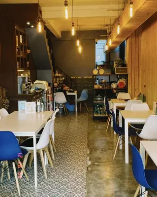 a restaurant with white tables and blue chairs at The Space Hometel - Women Only in Pom Prap
