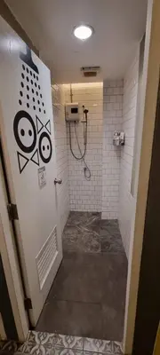 a bathroom with a shower with graffiti on the door at The Space Hometel - Women Only in Pom Prap