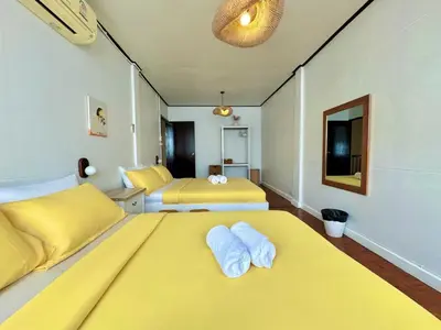 a hotel room with two beds with yellow sheets at Flow In House in Bangkok