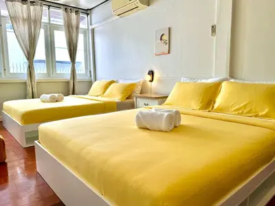 two beds in a room with yellow sheets at Flow In House in Bangkok
