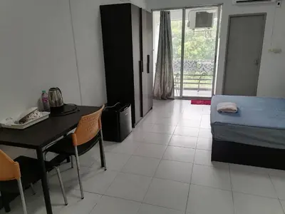 a room with a bed and a table and chairs at Merlin MANSION 107 in Ban Khlong Samrong