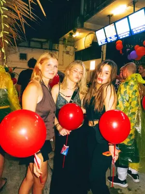 three girls holding red balloons at a party at AREA81 HIDEOUT Hostel Khaosan in Bangkok