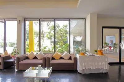 a living room with a couch and tables and windows at Anda Ramkhamhaeng By St James Hotel in Bangkok