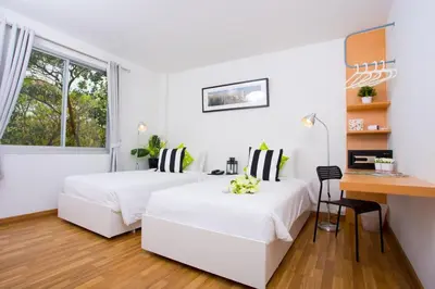 two beds in a white room with a desk at Anda Ramkhamhaeng By St James Hotel in Bangkok
