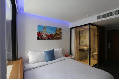 a bedroom with a large white bed with blue pillows at S Box Sukhumvit Hotel in Bangkok