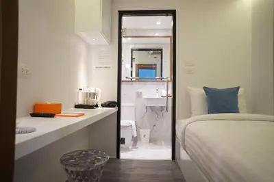 a bedroom with a bed and a bathroom with a sink at S Box Sukhumvit Hotel in Bangkok