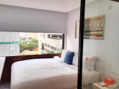 a bedroom with a bed and a large window at S Box Sukhumvit Hotel in Bangkok