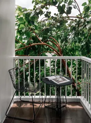 a table and chairs on a balcony with a tree at The StandardX, Bangkok Phra Arthit in Bangkok