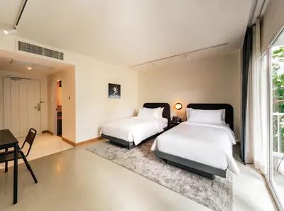 two beds in a room with a table and a desk at The StandardX, Bangkok Phra Arthit in Bangkok