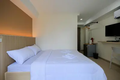 a large white bed in a room with a flat screen tv at Reezq Hostel in Ban Khlong Bang Sai