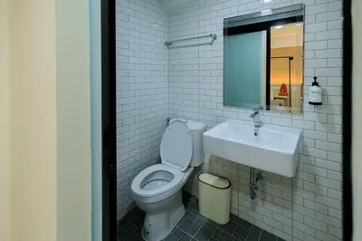 a white bathroom with a toilet and a sink at Reezq Hostel in Ban Khlong Bang Sai