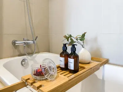three bottles of wine on a wooden tray next to a bath tub at Deluxe Suite 1BR Ultra Fast WiFi BTS Thong Lor in Bangkok