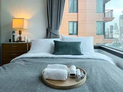 a bed with a tray with towels and a window at Expansive Luxury 2BR - Ultra Fast Wifi - Phrom Phong in Bangkok