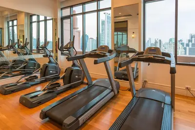 a row of treadmills in a gym with windows at Expansive Luxury 2BR - Ultra Fast Wifi - Phrom Phong in Bangkok