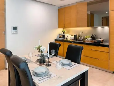 a dining room with a table with chairs and a kitchen at Transquil Residents 65 SQM - Ultra Fast Wifi - Silom in Bangkok