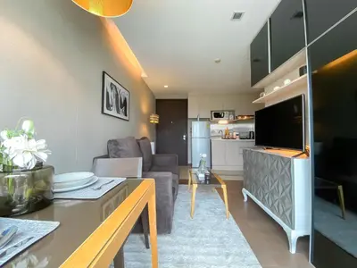 a living room with a couch a table and a tv at Tropical Haven 1BR - Ultra Fast WiFi - Thong Lo in Bangkok