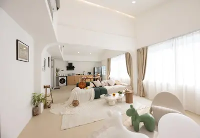 a white living room with a couch and a table at Ratchada Retreat Boutique Suites in Bangkok