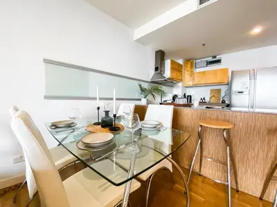 a kitchen with a glass table and white chairs at Downtown View 65 SQM - Ultra Fast Wifi - Sathorn in Bangkok