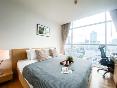 a bedroom with a bed with a desk and a window at Downtown View 65 SQM - Ultra Fast Wifi - Sathorn in Bangkok