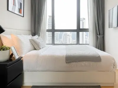 a bedroom with a white bed with a large window at Stylish Modern 1BR - BTS Phrom Phong - Ultra Fast WiFi in Bangkok