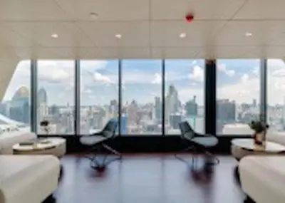 a room with chairs and tables in a building with windows at Luxury Skyview 1BR - Ultra Fast WiFi - Chit Lom in Bangkok