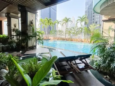 a swimming pool in a hotel with palm trees at Luxury Modern 2BR 145 sqm - BTS Asok - Ultra Fast WiFi in Bangkok