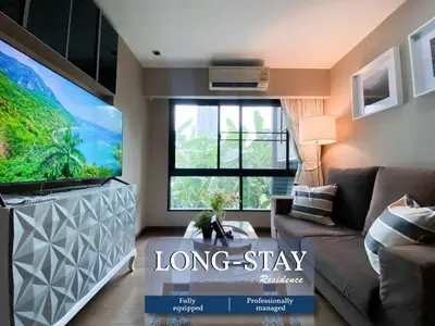 a living room with a large tv and a couch at Tropical Paradise 1BR - Ultra Fast Wifi - Thong Lo in Bangkok