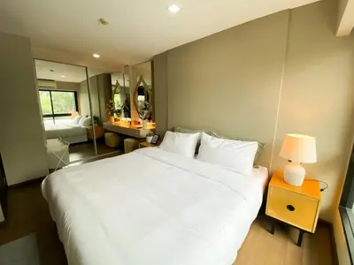 a bedroom with a large white bed and a table with a lamp at Tropical Paradise 1BR - Ultra Fast Wifi - Thong Lo in Bangkok