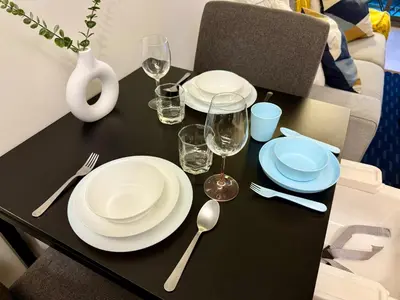 a black table with white plates and glasses and silverware at Cozy Spacious 1BR 3pax GardenView, 700m BTS ThongLo, Samitivej, SKV49, Fast wifi in Bangkok