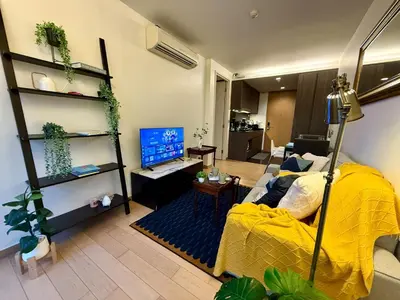 a living room with a yellow bed and a television at Cozy Spacious 1BR 3pax GardenView, 700m BTS ThongLo, Samitivej, SKV49, Fast wifi in Bangkok