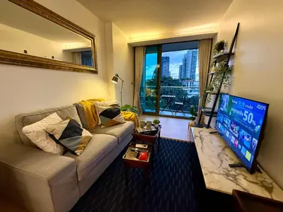 a living room with a couch and a flat screen tv at Cozy Spacious 1BR 3pax GardenView, 700m BTS ThongLo, Samitivej, SKV49, Fast wifi in Bangkok