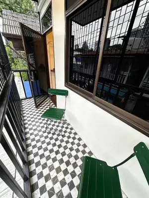 two green chairs sitting on a porch with a checkered floor at Twenty-one BKK House in Bang Kapi