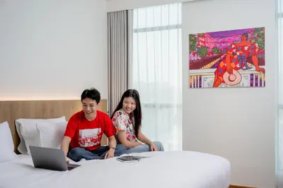 a man and a girl sitting on a bed with a laptop at Lub d Bangkok Chinatown - Steps from Sam Yod MRT Station in Bangkok