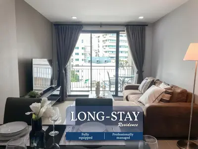 a living room with a long stay sign on a table at 2Br Modern Comfort at Vibrant Asok BTS Station in Bangkok