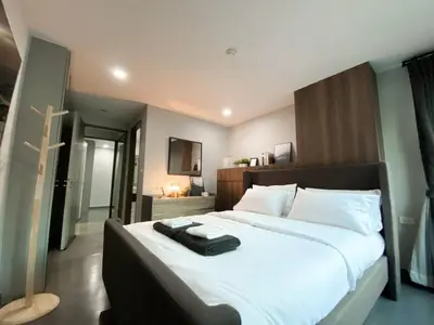a bedroom with a large bed with a black suitcase on it at 2Br Modern Comfort at Vibrant Asok BTS Station in Bangkok