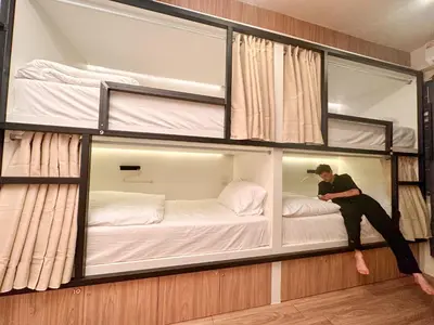 a man sitting on a bunk bed in a room at Bangkok Neighborhood Hostel in Bangkok