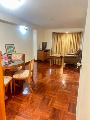 a living room with wooden floors and a table and chairs at Rent Omni Tower Apartments Nana Bangkok - Prime Sukhumvit location in Bangkok