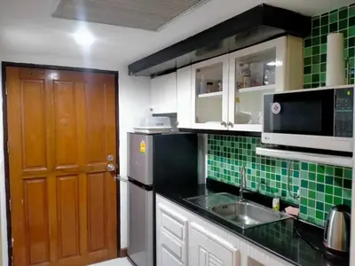 a kitchen with green tiled walls and a brown door at Rent Omni Tower Apartments Nana Bangkok - Prime Sukhumvit location in Bangkok