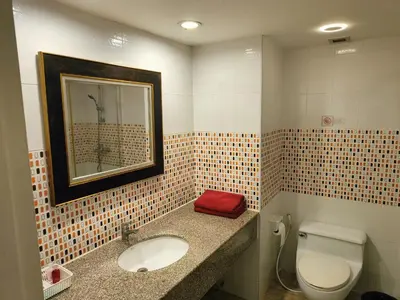 a bathroom with a toilet and a sink and a mirror at Rent Omni Tower Apartments Nana Bangkok - Prime Sukhumvit location in Bangkok