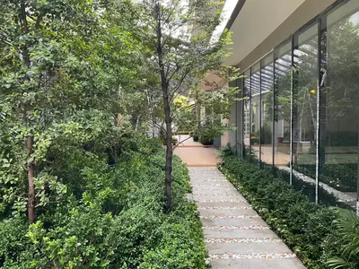 a walkway in front of a building with trees at 35 Bow Hotel in Ban Bang Bamru