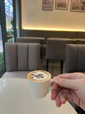 a person holding a cup of coffee on a table at 35 Bow Hotel in Ban Bang Bamru