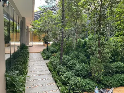 a garden with a stone walkway next to a building at 35 Bow Hotel in Ban Bang Bamru