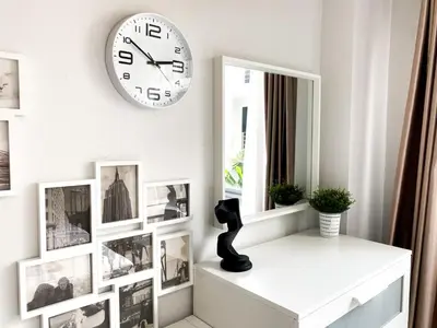 a clock on a wall above a shelf with pictures at Contemporary 53 SQM - BTS Thong Lo - Ultra Fast WiFi in Bangkok