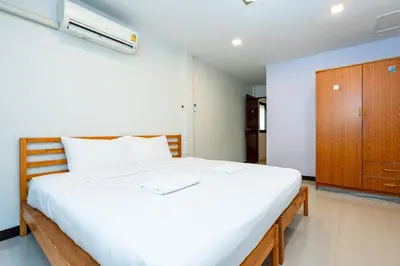 a bedroom with a large white bed and a wooden cabinet at xx The Hidden Sao Chingcha - เดอะ ฮิดเด้น เสาชิงช้า in Bangkok