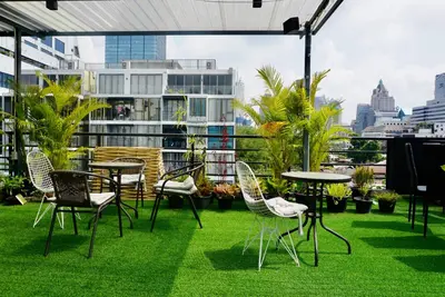 a patio with chairs and tables on the grass at Hash Apartment Silom Soi 3 triple room in Bang Rak