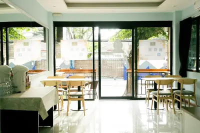 a restaurant with tables and chairs and a large window at Cozy Stay Inn in Bang Kapi